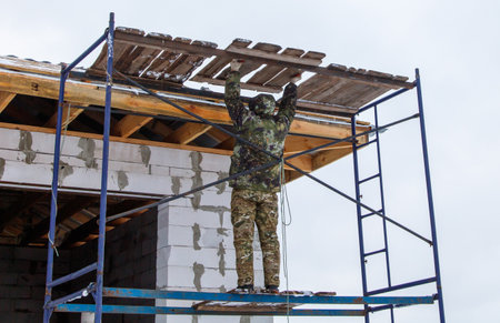 A man in camouflage is working on a building. Scene is serious and focusedの写真素材