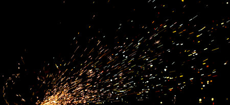 A black background with a lot of sparks and fire. The sparks are scattered all over the background,...