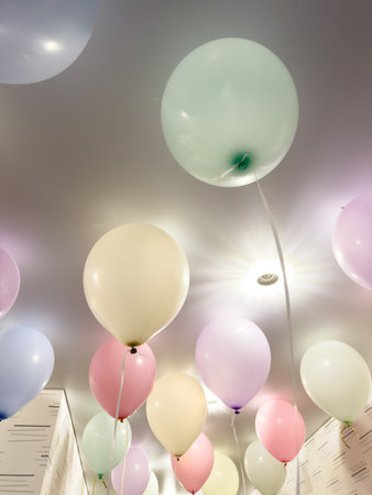 A bunch of balloons in different colors are floating in the air. The balloons are scattered all over the ceiling, creating a festive and lively atmosphere. The variety of colorsの写真素材