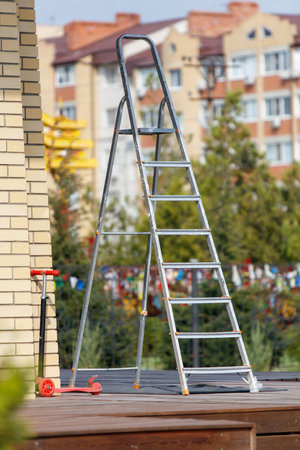A ladder is leaning against a brick building. The ladder is tall and has a metal pole at the topの写真素材