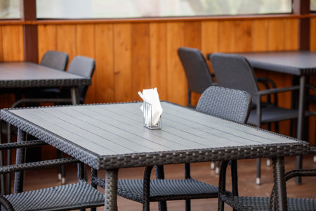 A table with a napkin on it and a silverware tray. The table is surrounded by chairs