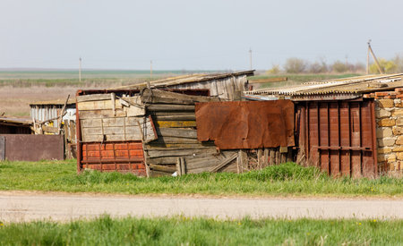 A group of old, dilapidated buildings sit in a field. The buildings are made of wood and metal, and they appear to be in a state of disrepair. Concept of abandonment and neglectの写真素材