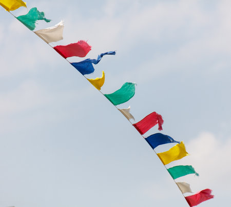 A colorful banner with a blue stripe and yellow and red stripes. The banner is hanging from a pole and is in the skyの写真素材
