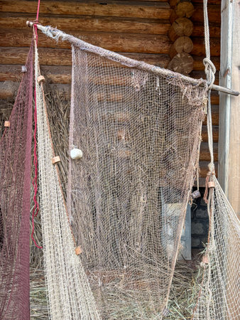 A large piece of netting is hanging from a wooden beam. The netting is made of a brown and white materialの写真素材