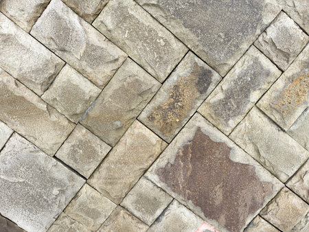 A stone wall with a pattern of squares and triangles. The wall is made of gray and brown stones