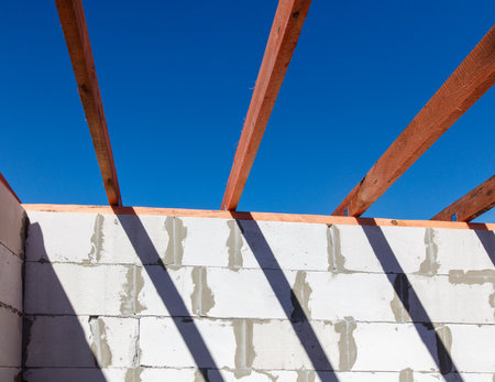 A blue sky with a wooden beam above a white wall. The beam is made of wood and is visible from the groundの写真素材