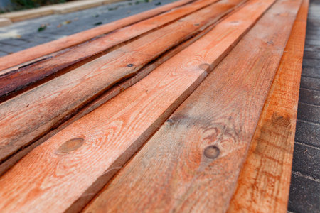 A row of wooden boards with a brownish color. The boards are arranged in a line and are placed on a concrete surfaceの写真素材