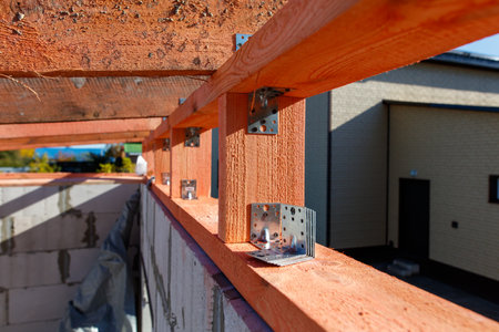 A wooden beam with nails holding it to a wall. The beam is orange and has a lot of nails