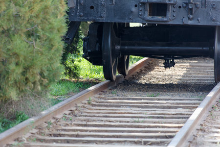A train is on the tracks and the wheels are on the ground. The train is black and the tracks are brownの写真素材