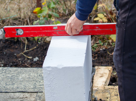 A man is using a red level to measure a white block. Concept of precision and accuracy, as the man...