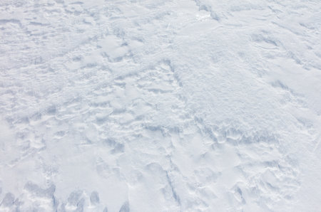 A snow covered ground with a white snowflake on it. The snow is very light and fluffyの写真素材