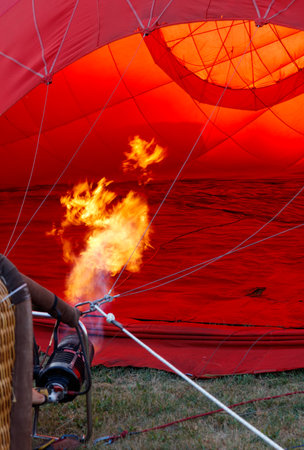 A man is holding a lighter near a red balloon. The balloon is filled with hot airの写真素材