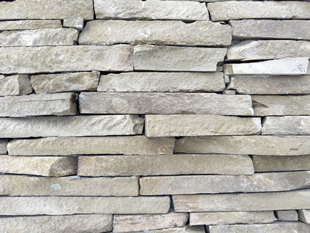 A wall made of stone blocks with a gray color. The wall is made of many blocks and has a rough...