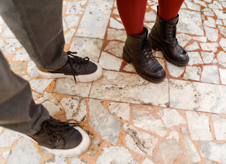 Two people standing next to each other with their feet on the ground. One person is wearing black...