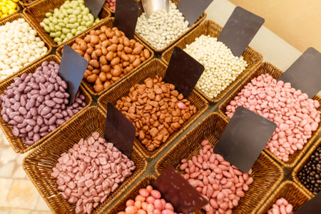 A basket of assorted nuts and seeds are displayed in a store. The nuts are in various colors and sizes, including almonds, cashews, and peanuts. The display is organized and visually appealingの写真素材