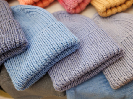 A row of knit hats in various colors, including blue, pink, and yellow. The hats are piled on top of each other, creating a colorful displayの写真素材