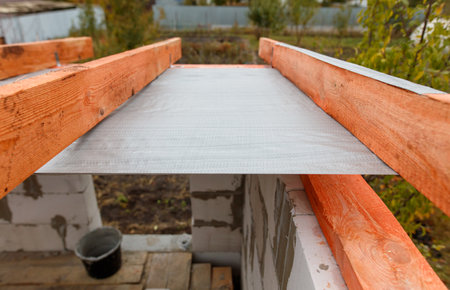 A wooden beam with a gray plastic sheet on top of it. The plastic sheet is likely being used to protect the wood from moisture or other elementsの写真素材