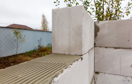 A white brick wall with a brown roof. The wall is being built with cement blocksの写真素材
