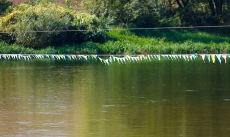 A long line of colorful flags are floating on the surface of a lake. The scene is peaceful and...