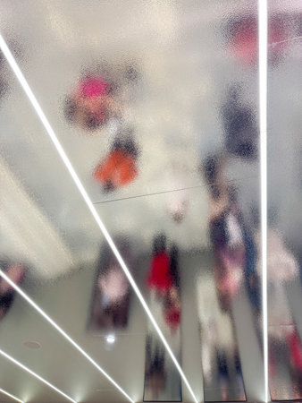 A blurry image of people in a room with a light shining on them. The people are wearing red and orange clothingの写真素材