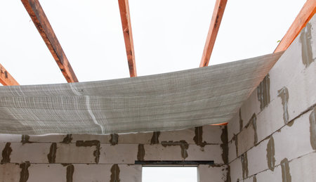 A gray and white tarp is stretched across the ceiling of a room. The tarp is covering a wooden beam...