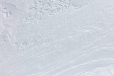 A snow covered ground with a few footprints. The snow is white and the ground is covered in it