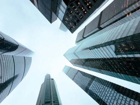 A city skyline with tall buildings and a cloudy sky. The buildings are all made of glass and are very tallの写真素材