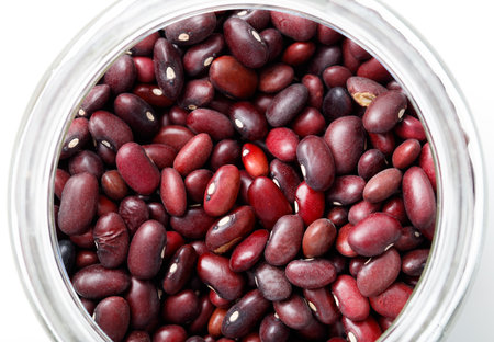 A jar full of red beans. The beans are spread out and are of different sizes. The jar is almost full, with only a small portion of the beans visibleの写真素材