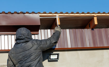 A man in a black coat is working on a roof. Concept of hard work and dedication, as the man is...