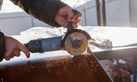 A man is using a power tool to cut a piece of metal. Concept of precision and control as the man...