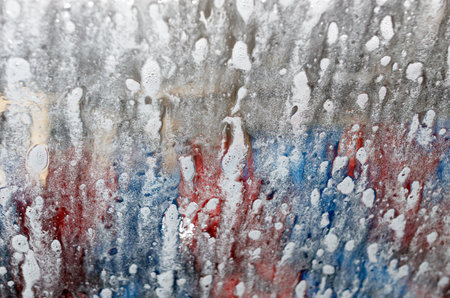 The image shows a surface with a lot of spray paint on it. The spray paint is in the form of white dots and red and blue splatters. The surface appears to be wet.の写真素材