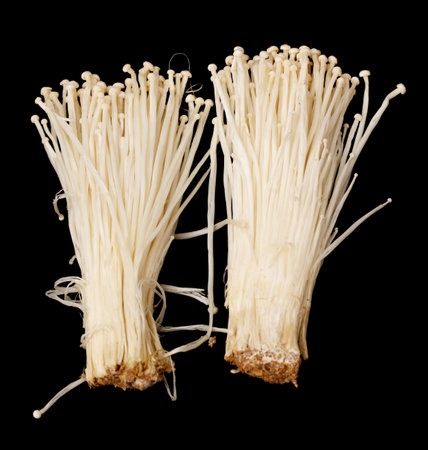 Two bunches of white asparagus are shown on a black background. The asparagus are fresh and appear...