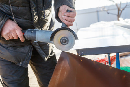 A man is using a power tool to cut a piece of metal. Concept of precision and focus as the man...