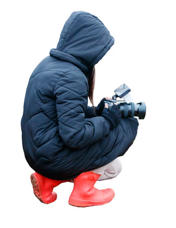 A woman in a black coat and red boots is taking a picture with a camera. Concept of adventure and exploration, as the woman is likely capturing a moment in a new or unfamiliar locationの写真素材