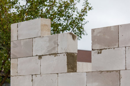A wall made of white bricks with a small window in the middle. The wall is unfinished and has a...