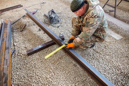 A man is measuring a piece of metal with a tape measure.