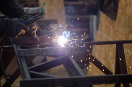A man is welding metal with a torch. Concept of danger and risk, as the man is working with a...
