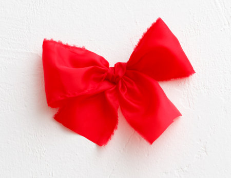 A red ribbon with a bow is on a white background. The ribbon is frilly and has a red bowの写真素材