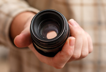 A person is holding a camera lens. The person appears to be a photographer or a camera enthusiast, as they are holding the lens with care and attentionの写真素材