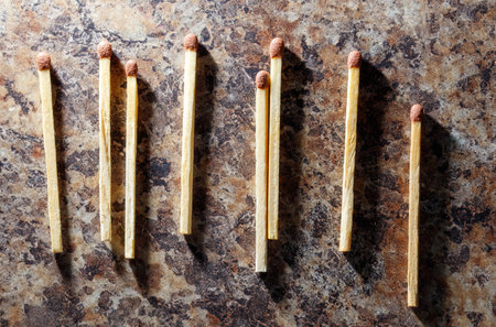 A row of matches with a small piece of wood on top of them. The wood is slightly larger than the...