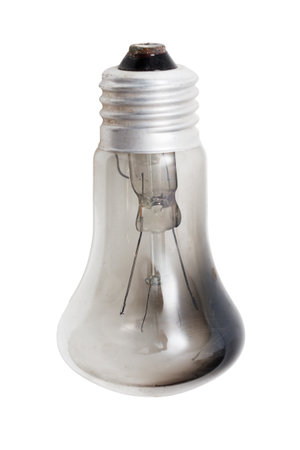 A light bulb is sitting on a white background. The bulb is old and has a blackened tipの写真素材