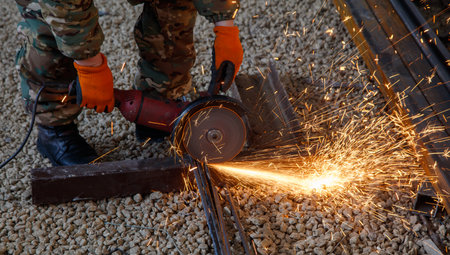 A man is cutting metal with a saw. The sparks from the saw are flying everywhere. The scene is...