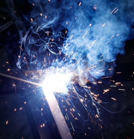 A blue smoke cloud is rising from a welding machine. The smoke is thick and billowing, creating a...