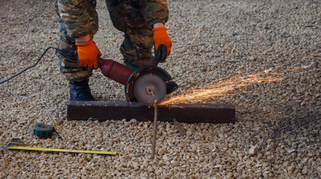 A man is using a power tool to cut a piece of wood. Concept of focus and determination as the man works to complete his taskの写真素材