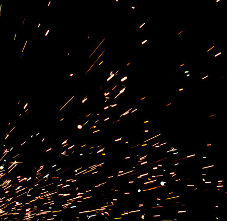 A black background with a lot of sparks and fire. The sparks are scattered all over the background, creating a sense of chaos and destruction. The image conveys a feeling of dangerの写真素材