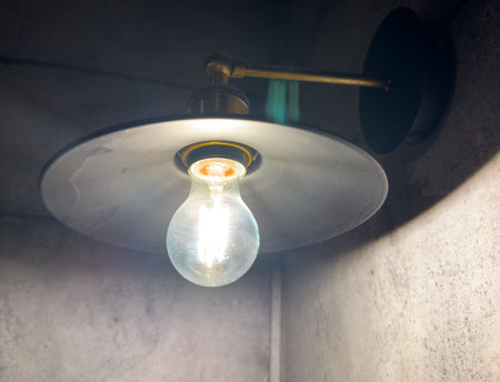 A light bulb is lit up in a room with a gray wall. The light is bright and illuminating the space