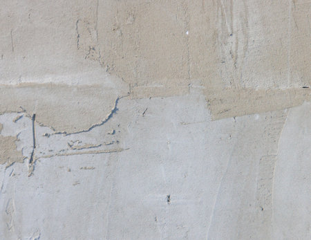 A wall with a rough texture and a white base. The wall is made of cement and has a gray colorの写真素材
