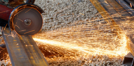 A piece of machinery is cutting through a metal bar. The sparks from the cutting process are flying...