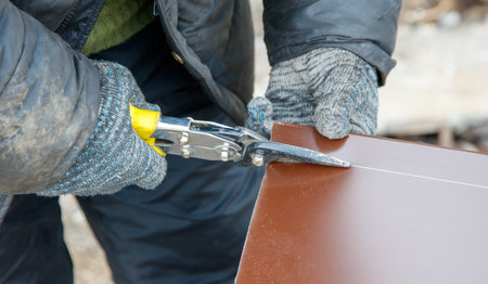 A man is cutting a piece of wood with a pair of scissors. Concept of precision and focus as the man carefully cuts the woodの写真素材