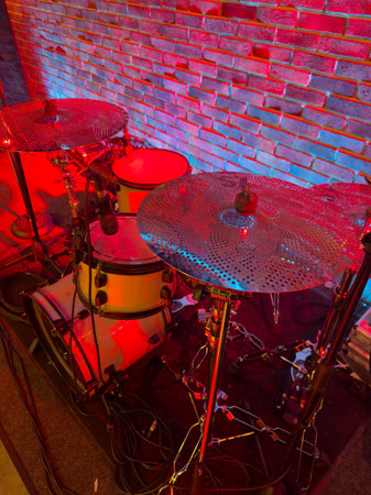 A drum set with a red brick wall in the background. The drums are red and whiteの写真素材